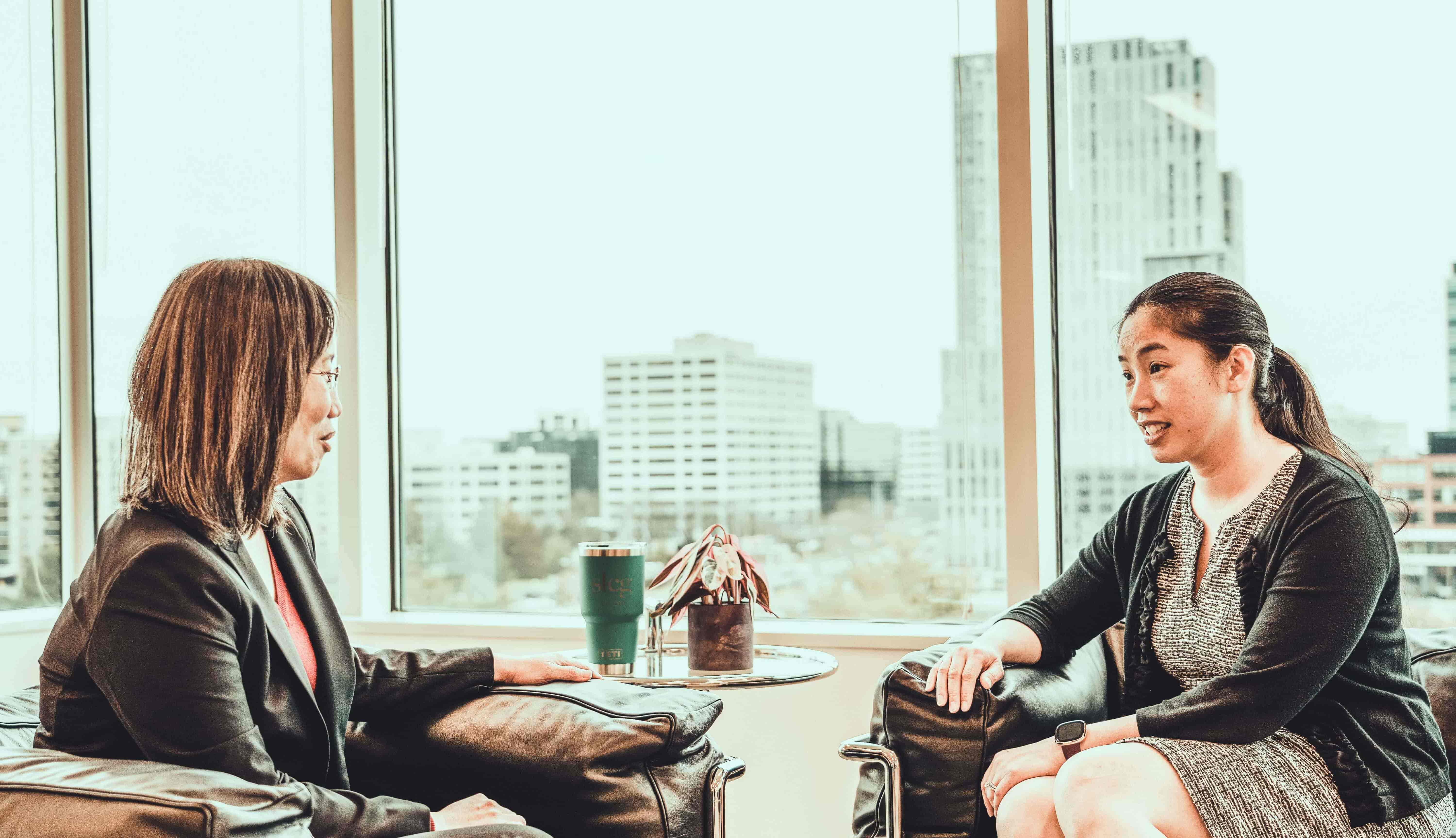 A group photo of two SLCG Economic Consulting employees discussing work by the window in the office.