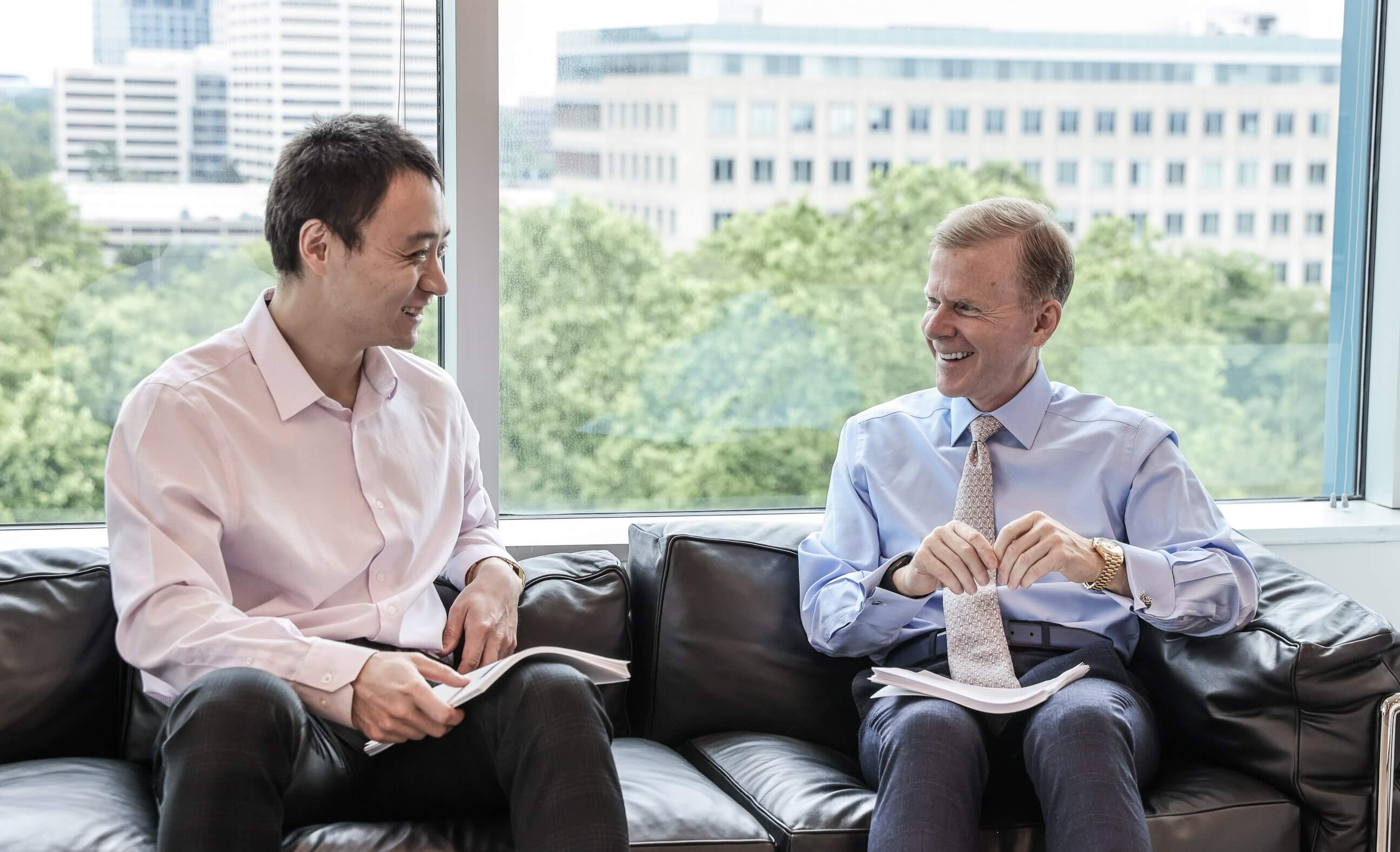 A photo of two of SLCG Economic Consulting's Principals talking on a couch.